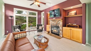 A living room with a fireplace, a television, a sofa, and a ceiling fan. - Caddy Corner MCA#1122-EV Charger, Golf Course Lake views, 2 blocks to beach. (Manzanita)