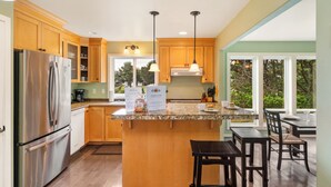 A modern kitchen with wooden cabinets, stainless steel appliances, and a granite countertop. - Caddy Corner MCA#1122-EV Charger, Golf Course Lake views, 2 blocks to beach. (Manzanita)