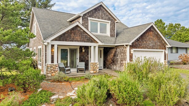 A two-story house with a stone foundation, a covered front porch, and a garage. - Caddy Corner MCA#1122-EV Charger, Golf Course Lake views, 2 blocks to beach. (Manzanita)