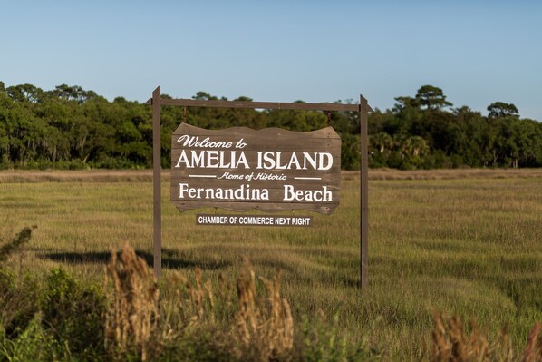 A wooden welcome sign for Amelia Island, indicating the location of Fernadina Beach and the Chamber of Commerce.
