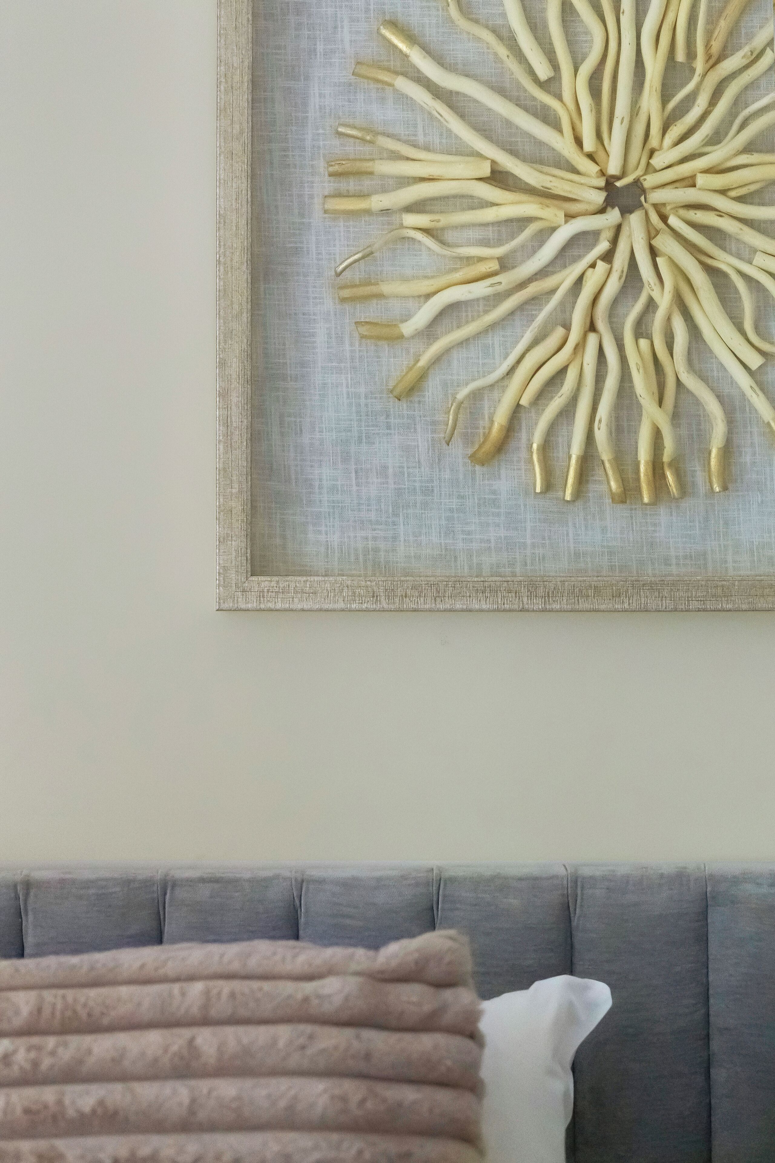 A framed abstract art piece with a central dark square surrounded by radiating lines on a textured background.