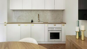 A modern kitchen with white cabinets, a marble backsplash, a stainless steel oven, and a wooden countertop. - Elite Apartments Korzeniowskiego seaside (Gdansk)