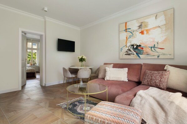 A modern living room with a beige sofa, a glass coffee table, and a large abstract painting on the wall. - Elite Apartments Korzeniowskiego seaside (Gdansk)