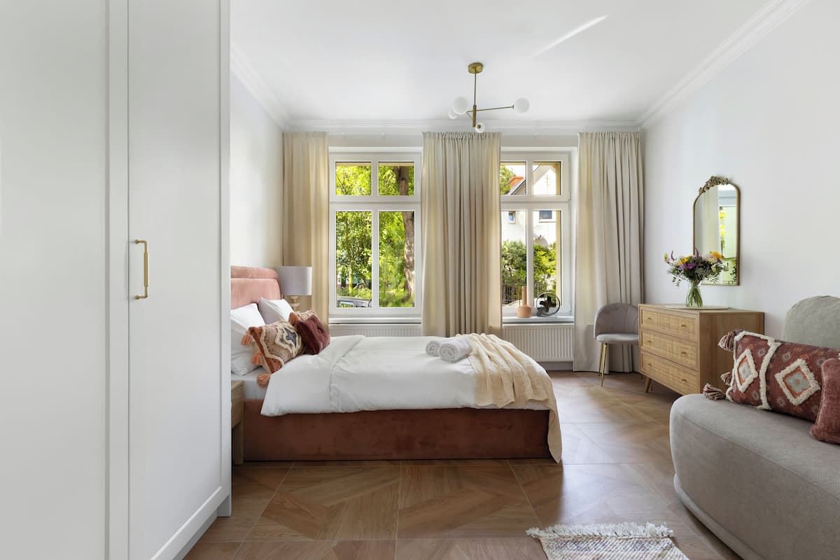 Um quarto com cama, penteadeira, cadeira e sofá.