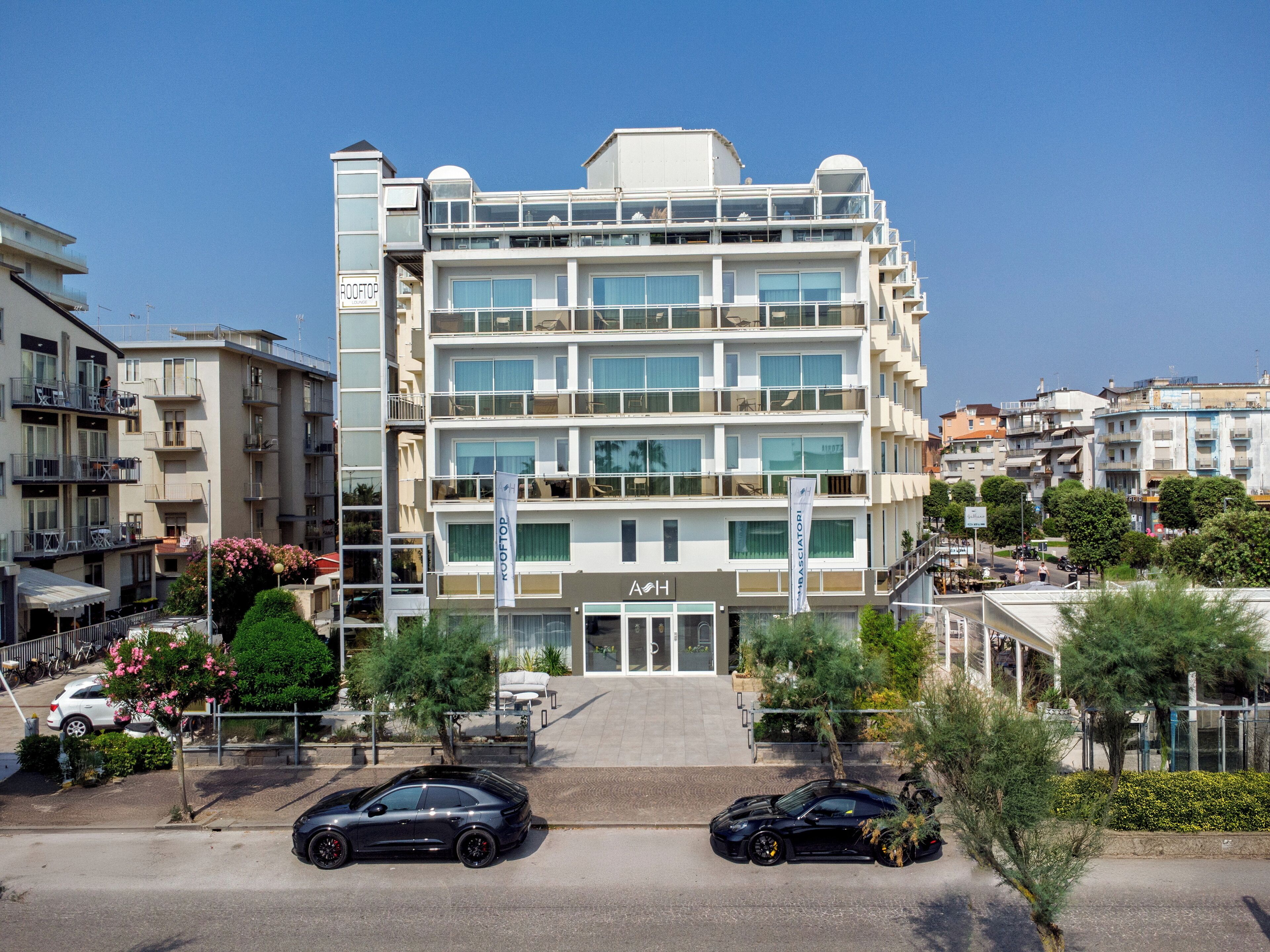 A multi-story hotel with balconies, a rooftop, and a ground-level entrance.
