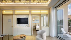 Ett modernt hotellrum med en stor TV, en matplats, en soffa och en balkong med utsikt.