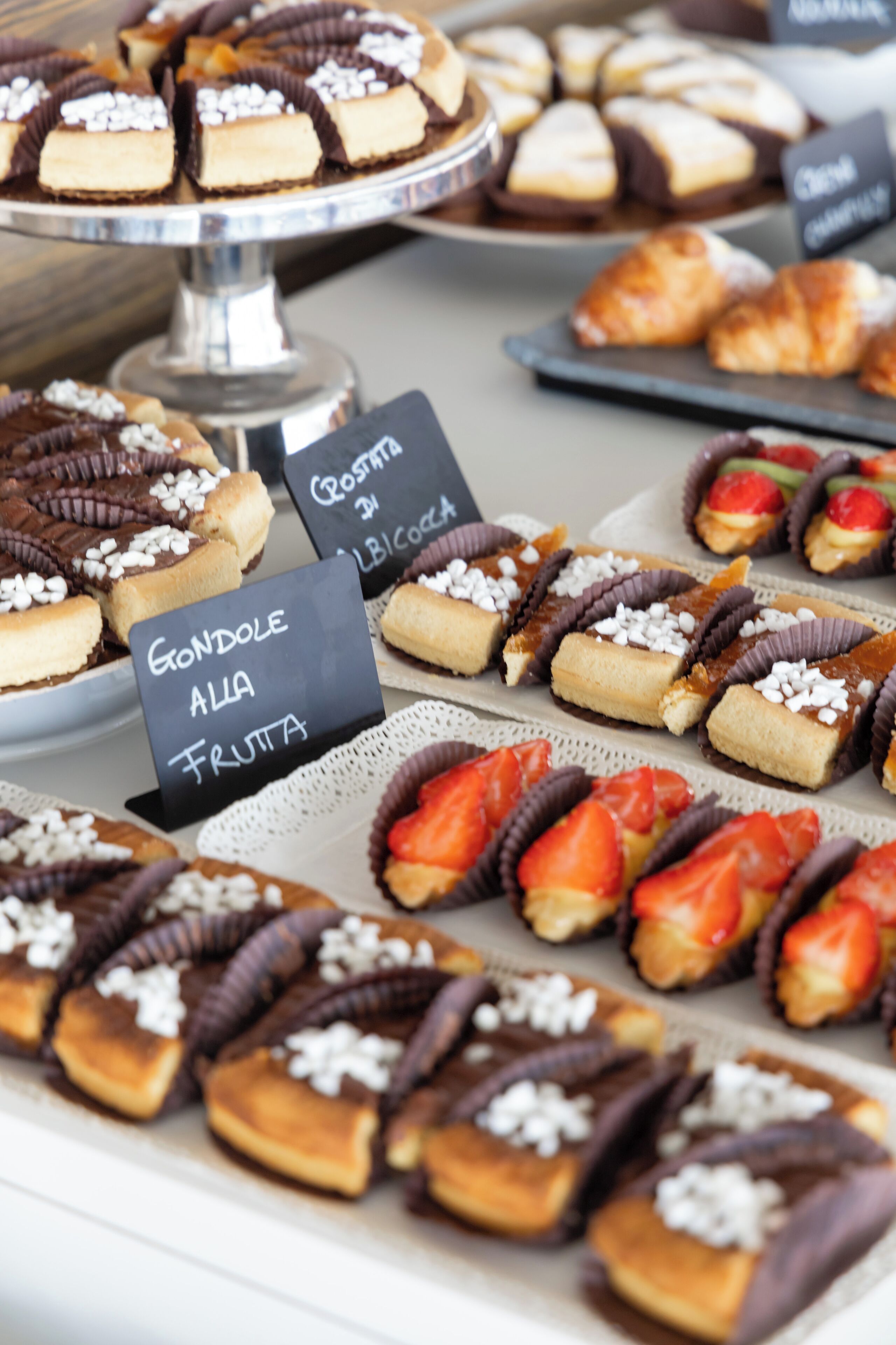 A variety of desserts on display, including chocolate-covered treats and fruit-topped pastries.