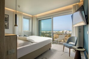 Una habitación de hotel moderna con una cama grande, una silla, una mesita y un televisor.