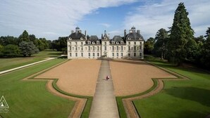 A large, symmetrical building with a central courtyard, surrounded by manicured lawns and trees. - Lodging Nature Camp Châteaux de la Loire (Cellettes)