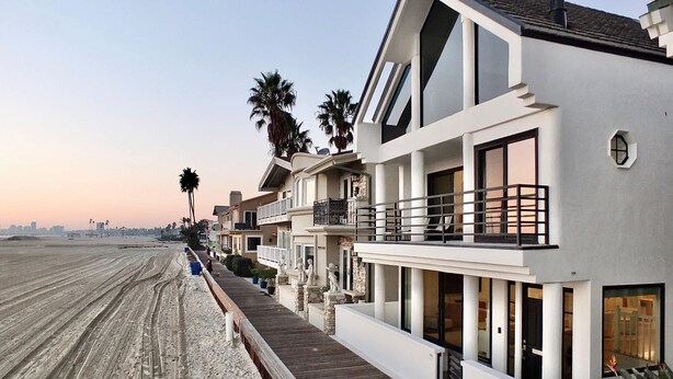 A beachfront property with a wooden boardwalk leading to a white building with balconies. - Beachfront Estate - LB Peninsula (Long Beach)
