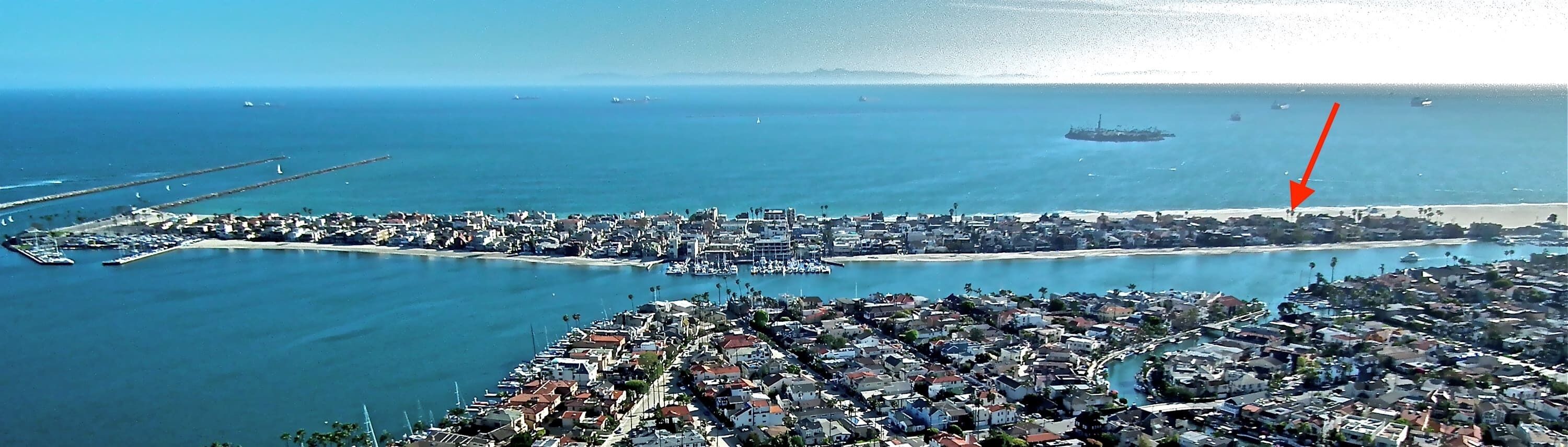 An aerial view of a coastal city with a marina, dense urban area, and a large body of water.