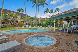 Piscina con hidromasaje, sillas de descanso y un área exterior cubierta con mesas y sillas.