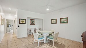Un coin repas avec une table ronde et des chaises, un ventilateur de plafond et des tableaux encadrés accrochés aux murs.