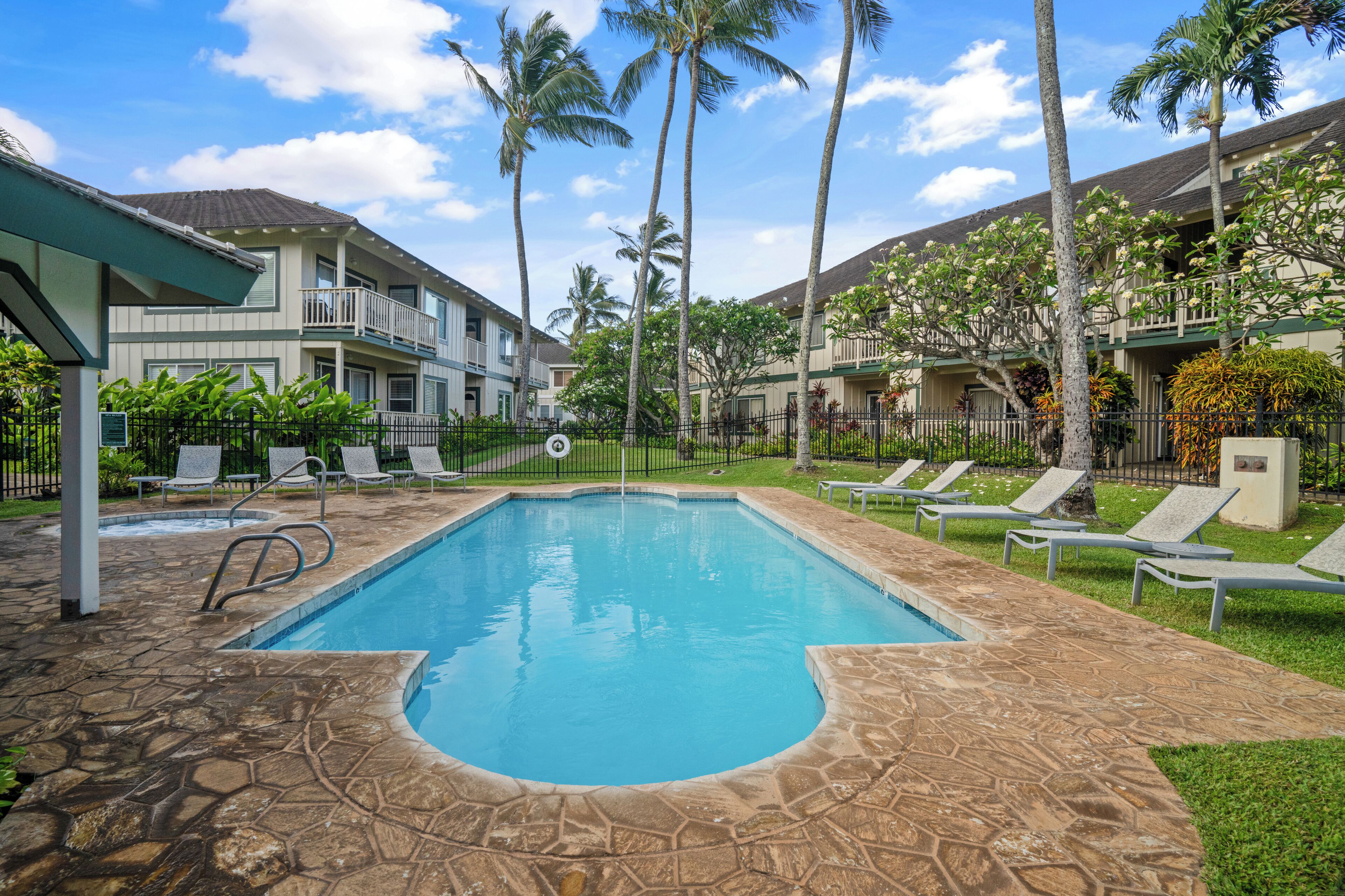 A swimming pool with lounge chairs and palm trees.