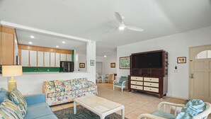 Un salon comprenant un canapé, une table basse, un téléviseur et un coin repas avec des chaises.