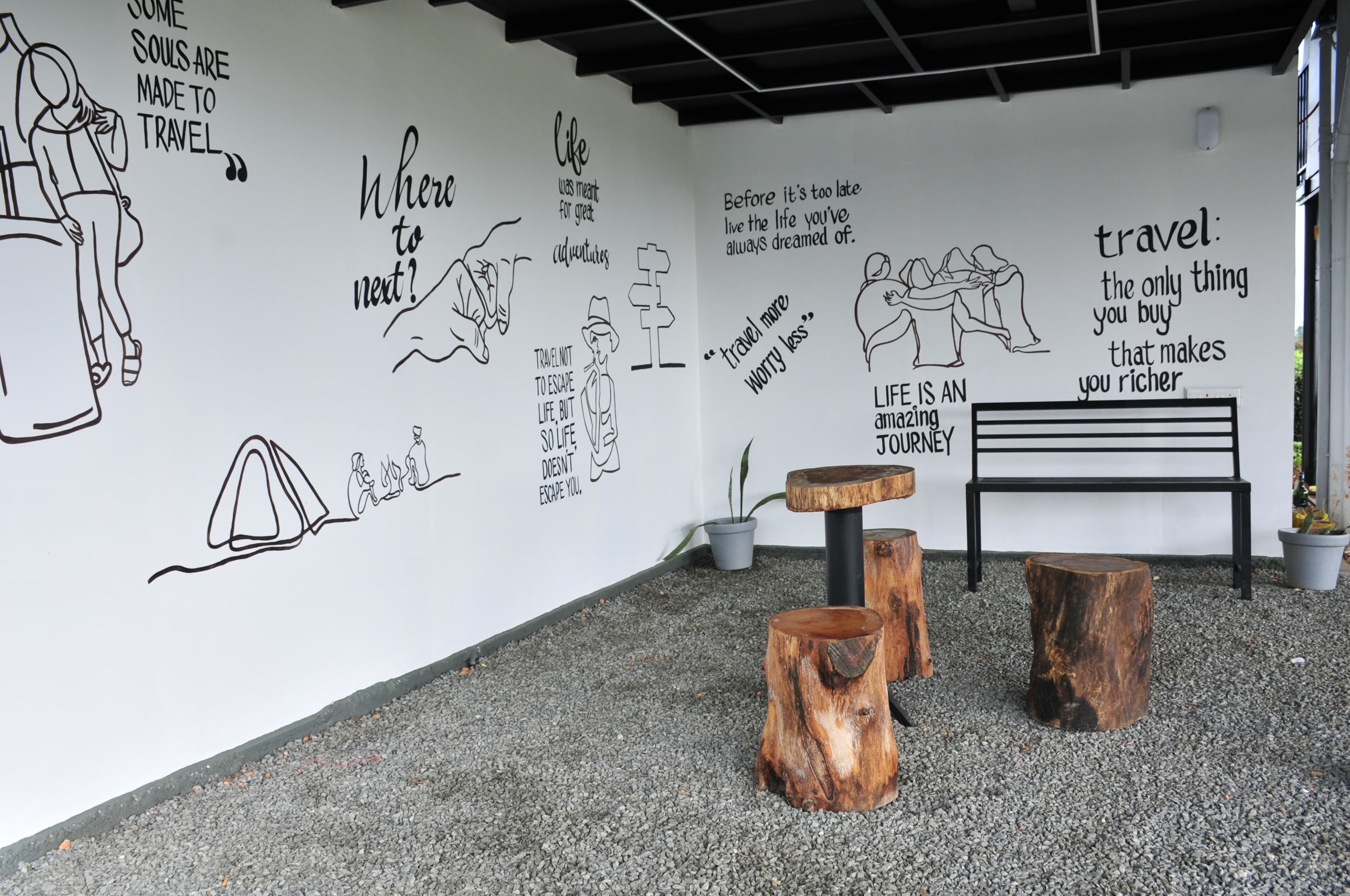 A wall with travel-related quotes and illustrations, a bench, and wooden stools in a modern interior setting.