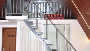 Un escalier moderne avec des rampes en verre menant à un étage supérieur en bois.