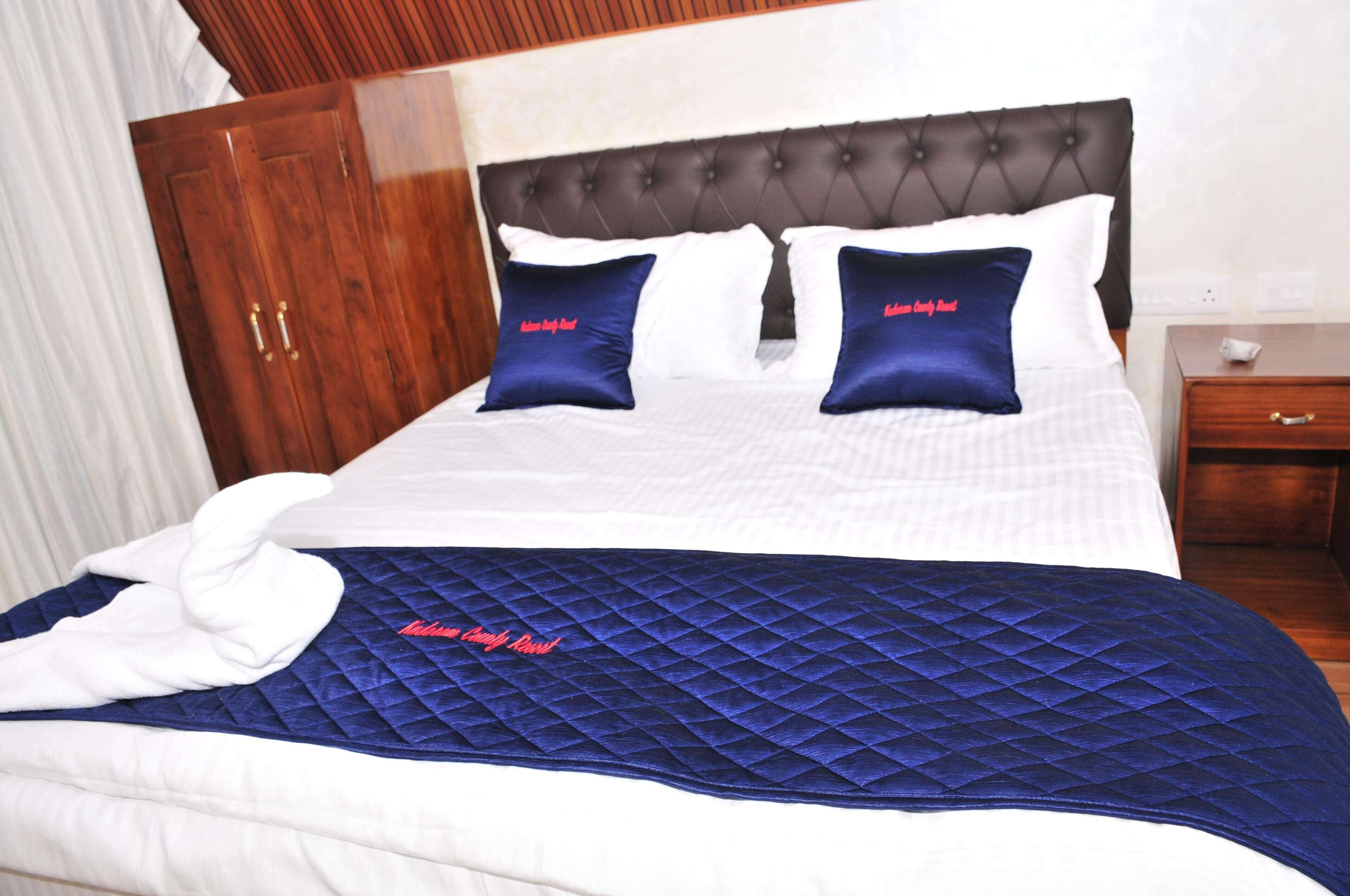 A hotel room with a bed, a wooden wardrobe, and a nightstand.