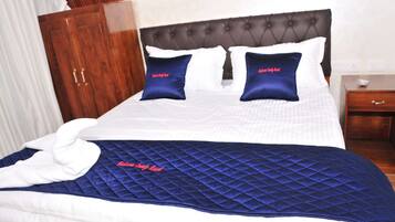 A hotel room with a bed, a wooden wardrobe, and a nightstand.