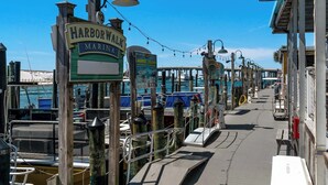 En marina med fortøjede både, en træpromenade og et skilt med teksten "Harbor Walk Marina".