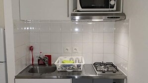Una cocina equipada con microondas, lavamanos y estufa a gas.