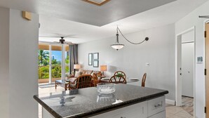 A modern kitchen with a central island, white cabinetry, and a dining area with wooden chairs and a table.