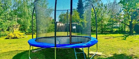 A trampoline with a safety net enclosure in a grassy outdoor area.