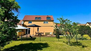 Een tweelaags huis met een rode dakbedekking, een omheinde achtertuin en een schotelantenne.