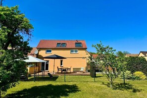 A two-story house with a red-tiled roof, a fenced backyard, and a satellite dish.