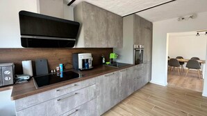A modern kitchen with a built-in oven, a coffee machine, and a microwave. - Ferienhaus Havelzeit in Werder an der Havel (Werder an der Havel)