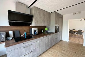 Uma cozinha moderna com forno embutido, máquina de café e micro-ondas.