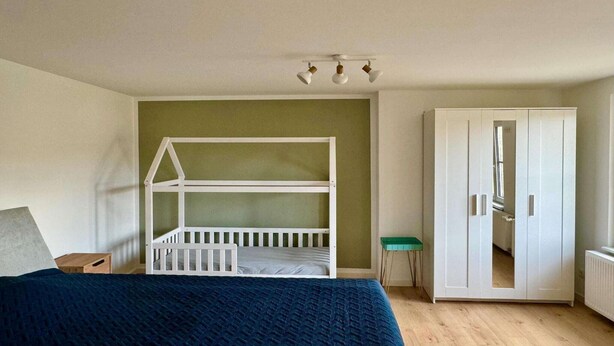 Een slaapkamer met een stapelbed, een kledingkast, een tafeltje en een radiator.
