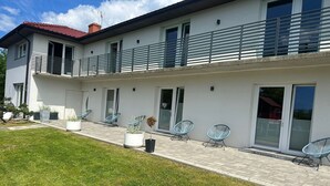 A modern two-story house with a balcony, potted plants, and outdoor seating. - Holiday apartments very close to the beach (Chlopy)