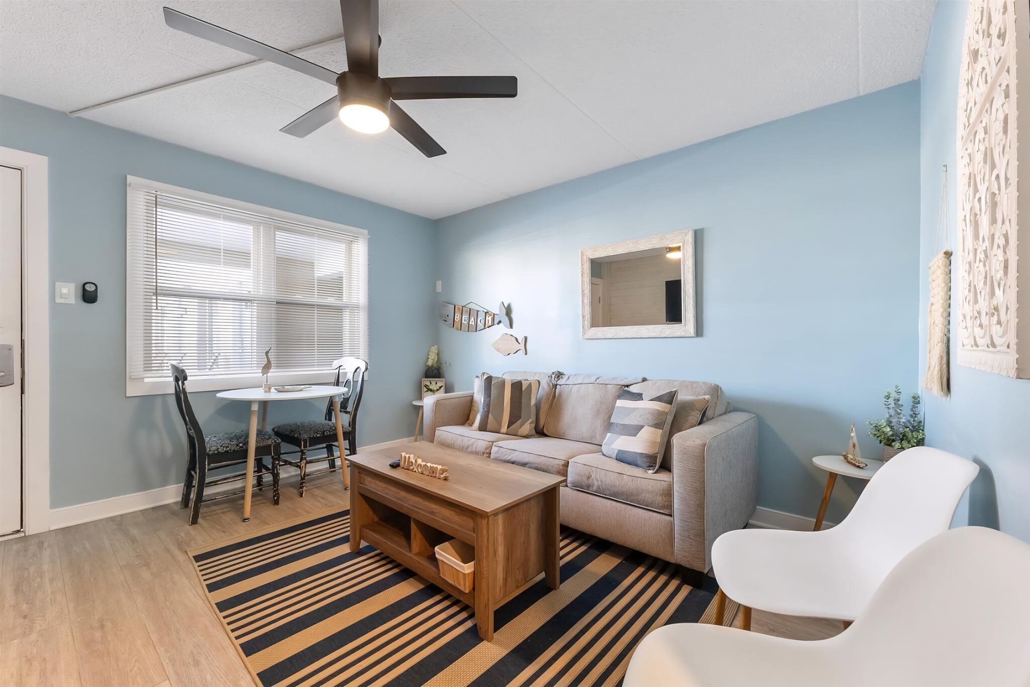 A living room with a ceiling fan, a sofa, a coffee table, and a dining area with a table and chairs.