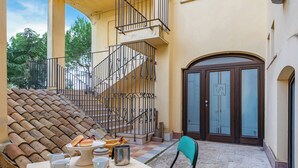 A courtyard with a table set for tea, a staircase, and a door with a sign. - Nella Apartment With Pool (Sannicandro di Bari)