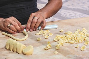 Hands shaping dough on a wooden surface with a rolling pin and a knife. - Nella Apartment With Pool (Sannicandro di Bari)