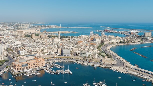 A coastal cityscape with a marina filled with boats, a prominent building with a dome, and a clear blue sky. - Nella Apartment With Pool (Sannicandro di Bari)