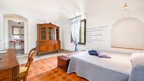 A bedroom with a bed, a wooden cabinet, a desk, and a window with a curtain. - Nella Apartment With Pool (Sannicandro di Bari)