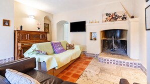 A living room with a fireplace, a sofa, a television, and a decorative wall. - Nella Apartment With Pool (Sannicandro di Bari)