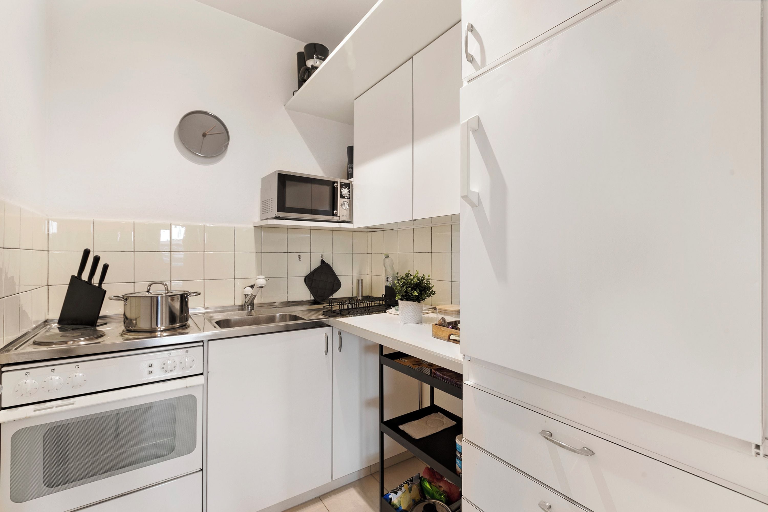 A modern kitchen with white cabinets, a microwave, a stove, and a sink.