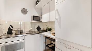 A modern kitchen with white cabinets, a microwave, a stove, and a sink.