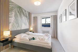 A modern hotel room with a large bed, bedside lamps, a window with curtains, and framed artwork on the wall. - Residenza Tasso Sul Lago in Castagnola (Lugano)