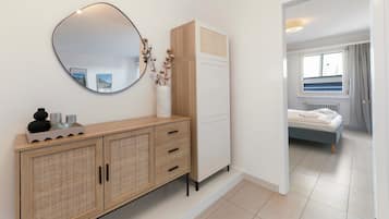 A bedroom with a bed, a wardrobe, a mirror, and a bedside table with decorative items.