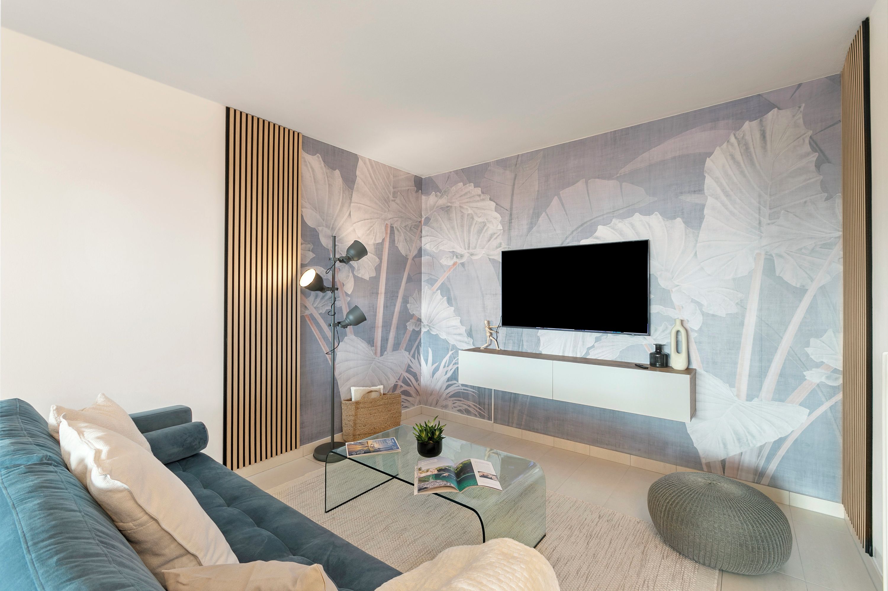 Un soggiorno moderno con divano, tavolino, TV a parete e pannello decorativo.