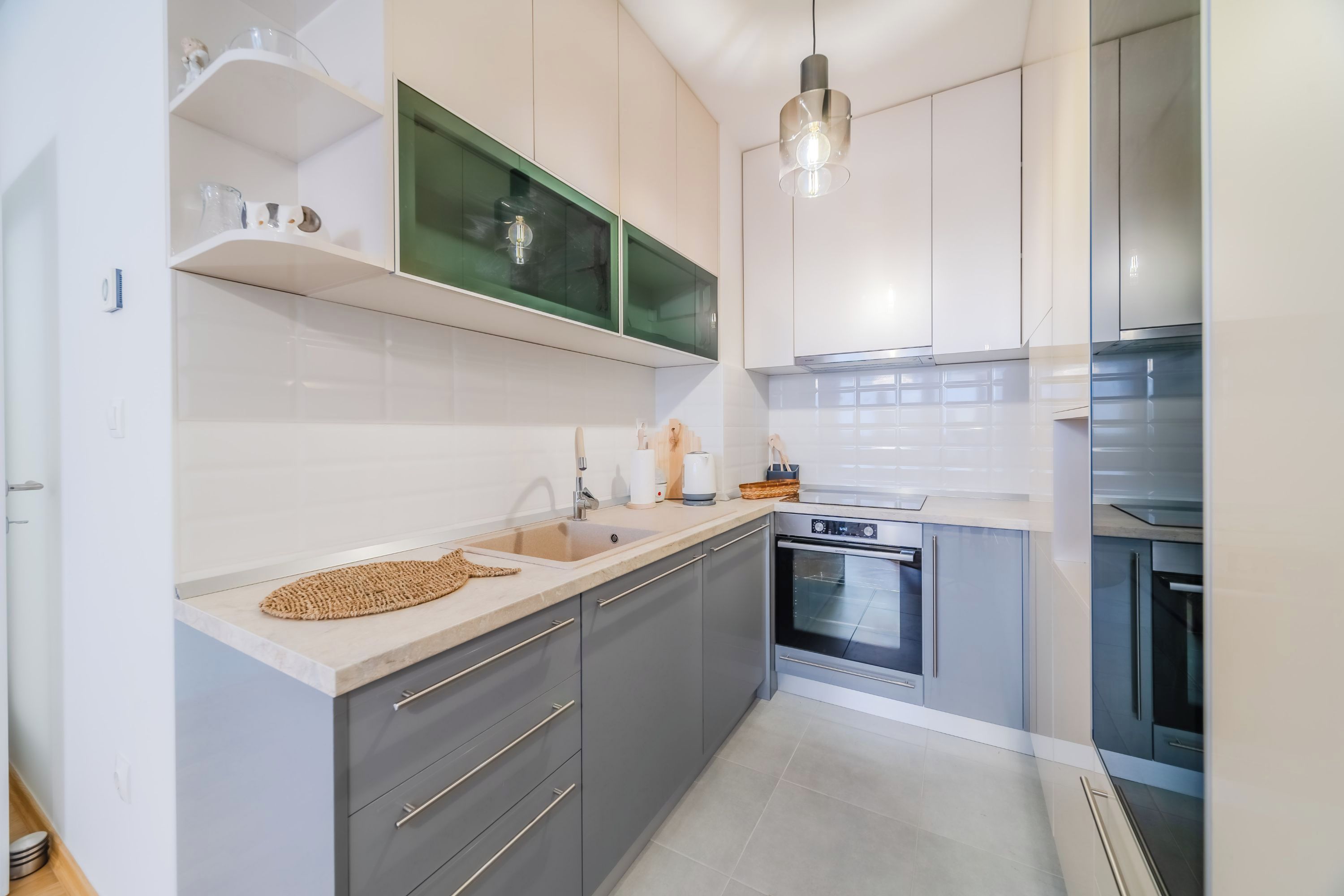 A modern kitchen with grey cabinets, a white countertop, and a built-in oven.