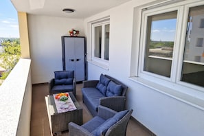 A balcony with wicker furniture, a table with fruits and flowers, and a grey cabinet. - Modern Oasis With Terrace (Zagreb)