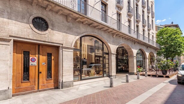 A building with a stone facade, large arched windows, and a wooden door with a sign. - Novos Arcadia 501 for 6 (Lugano)