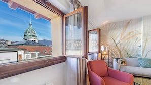 A room with a view of a dome building, a red armchair, a sofa, and a patterned wall. - Novos Arcadia 501 for 6 (Lugano)