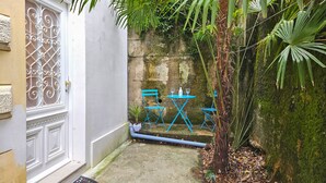 A courtyard with a white door, a stone wall, and a small table with chairs. - Sea and City Retreat Opatija (Opatija)