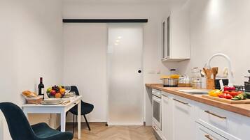 A modern kitchen with white cabinets, a wooden countertop, and a dining area with a table and chairs.